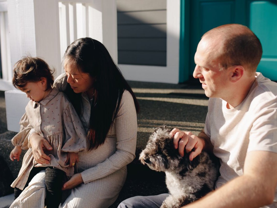 Familia sentada en los escalones de su casa / Family sitting on the front steps of their home